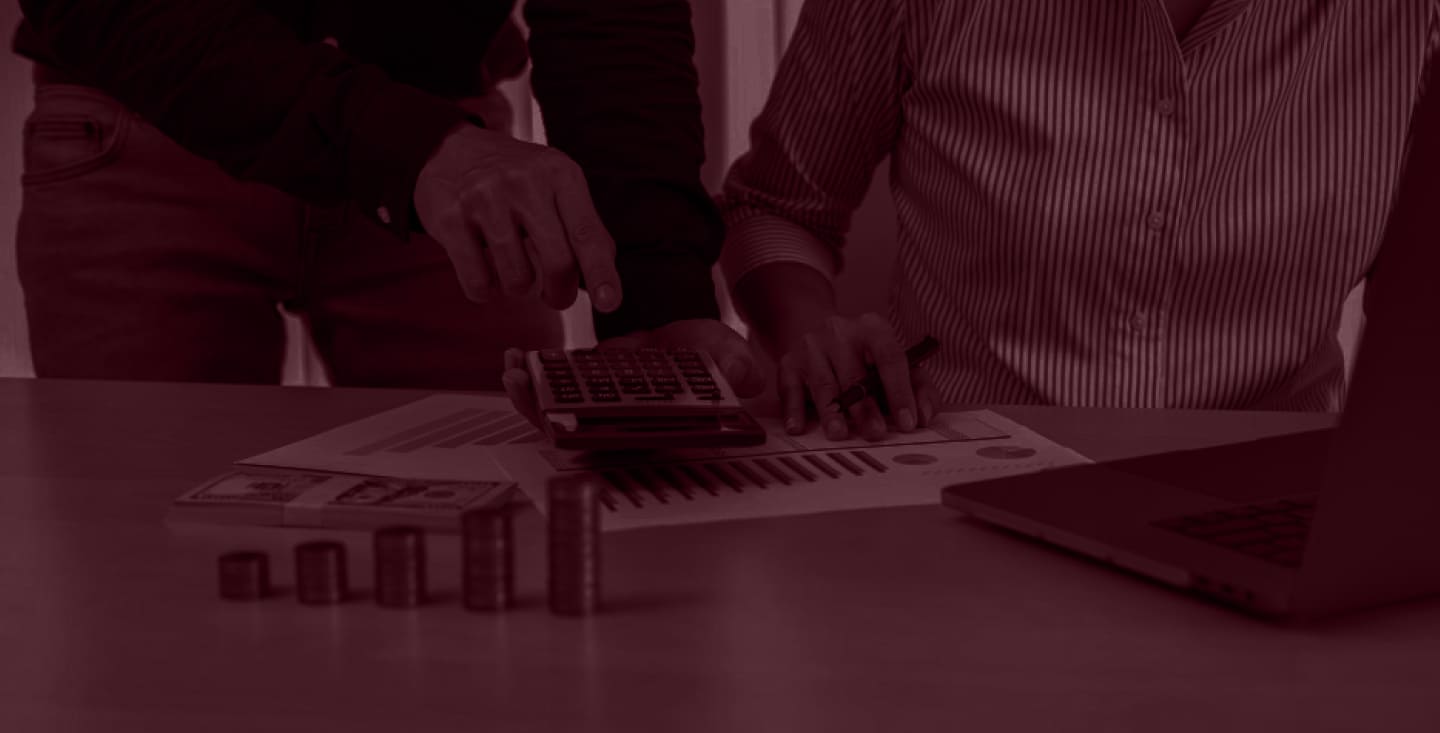 Two people reviewing mortgage paperwork with a calculator and stacks of coins